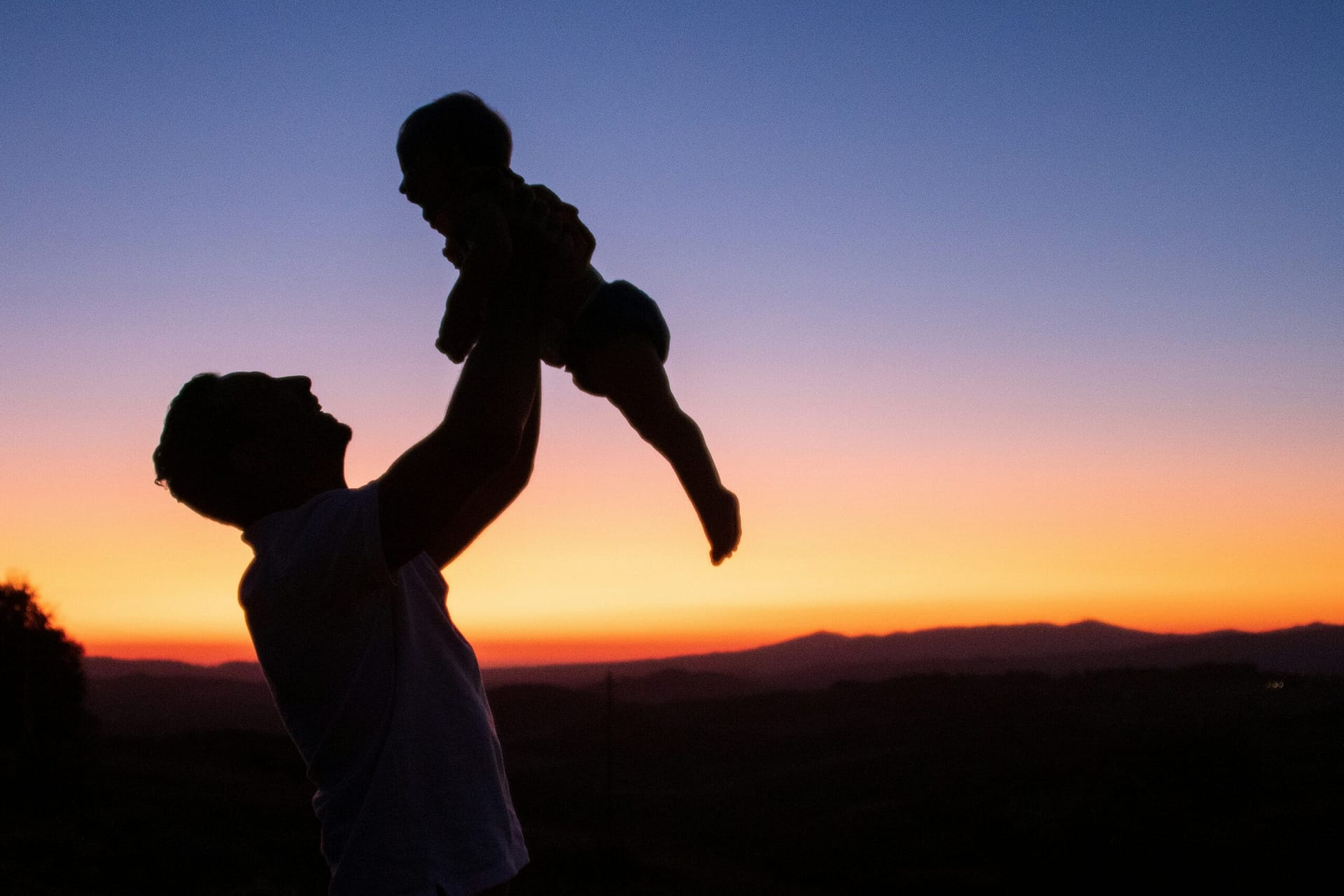 A father lifting his child against a sunset, hopeful after divorce