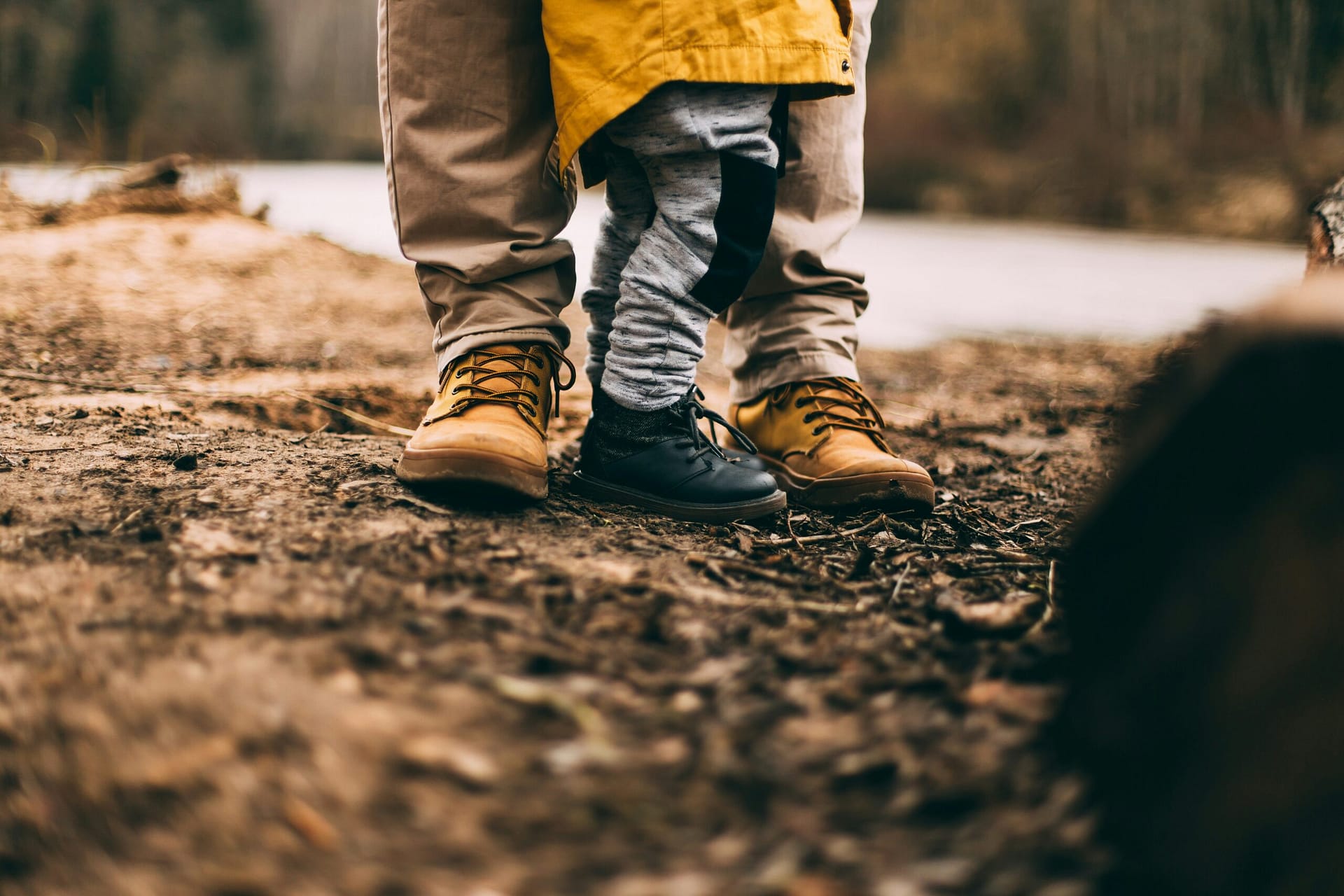 A divorced dad standing close with his young child outdoors, staying present as a father