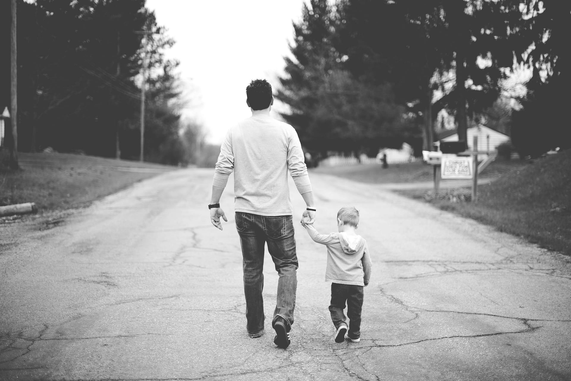 A father and his young son walking down a road together, moving forward after divorce
